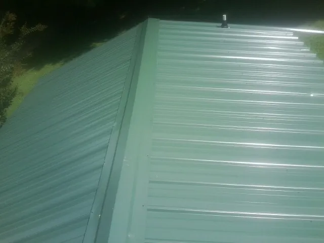 New green metal panels meeting at the ridge of a roof — Flat Roof Repair work by our crew in Ravenswood