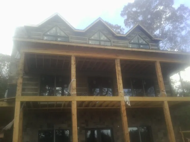 Dormers and porch framing on a large log home under construction — Roof Coating work by our crew in Ravenswood