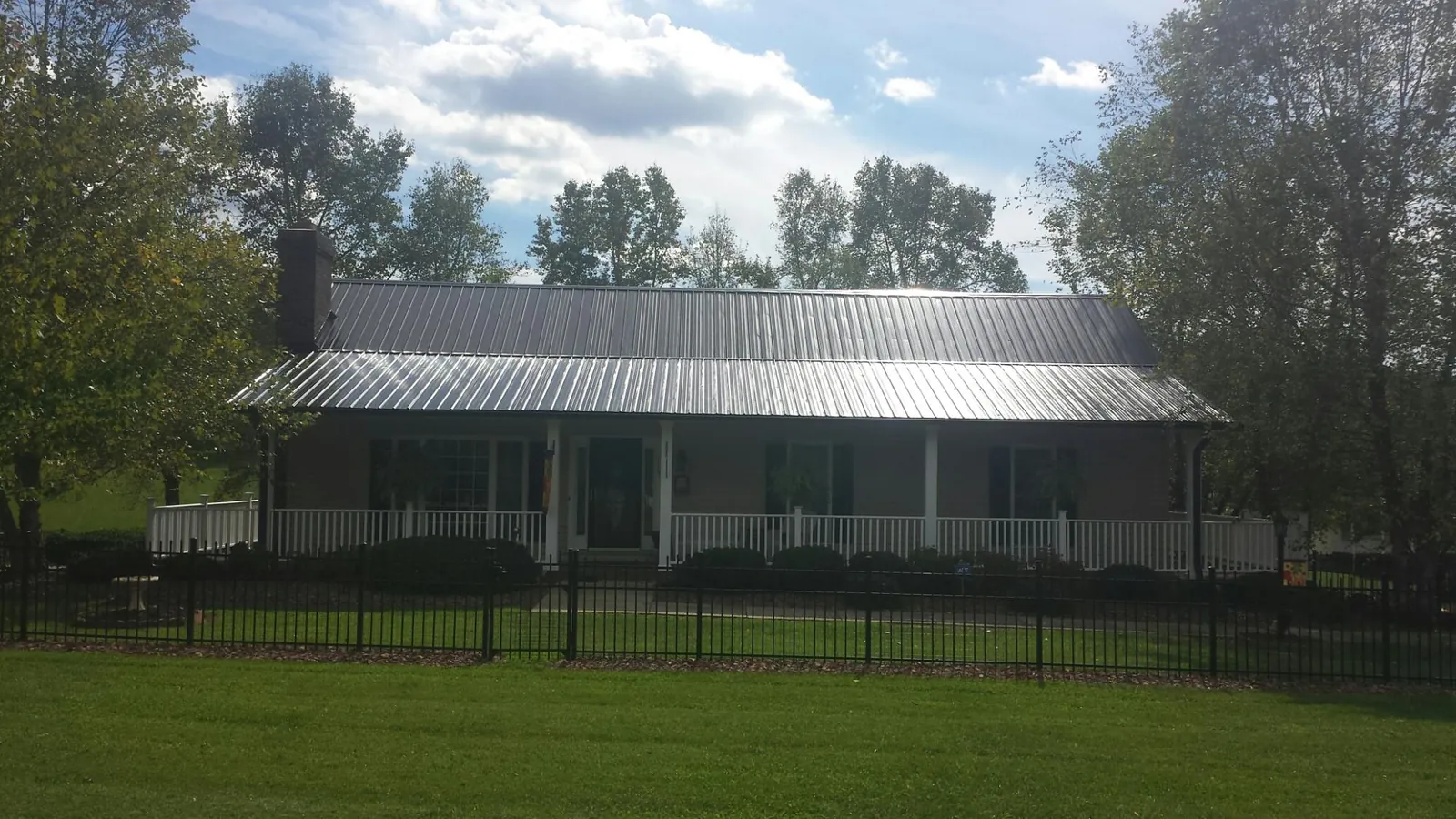 Gray metal roof on a brick ranch with a full width front porch — Gutter Guard Installation work by our crew in Ravenswood