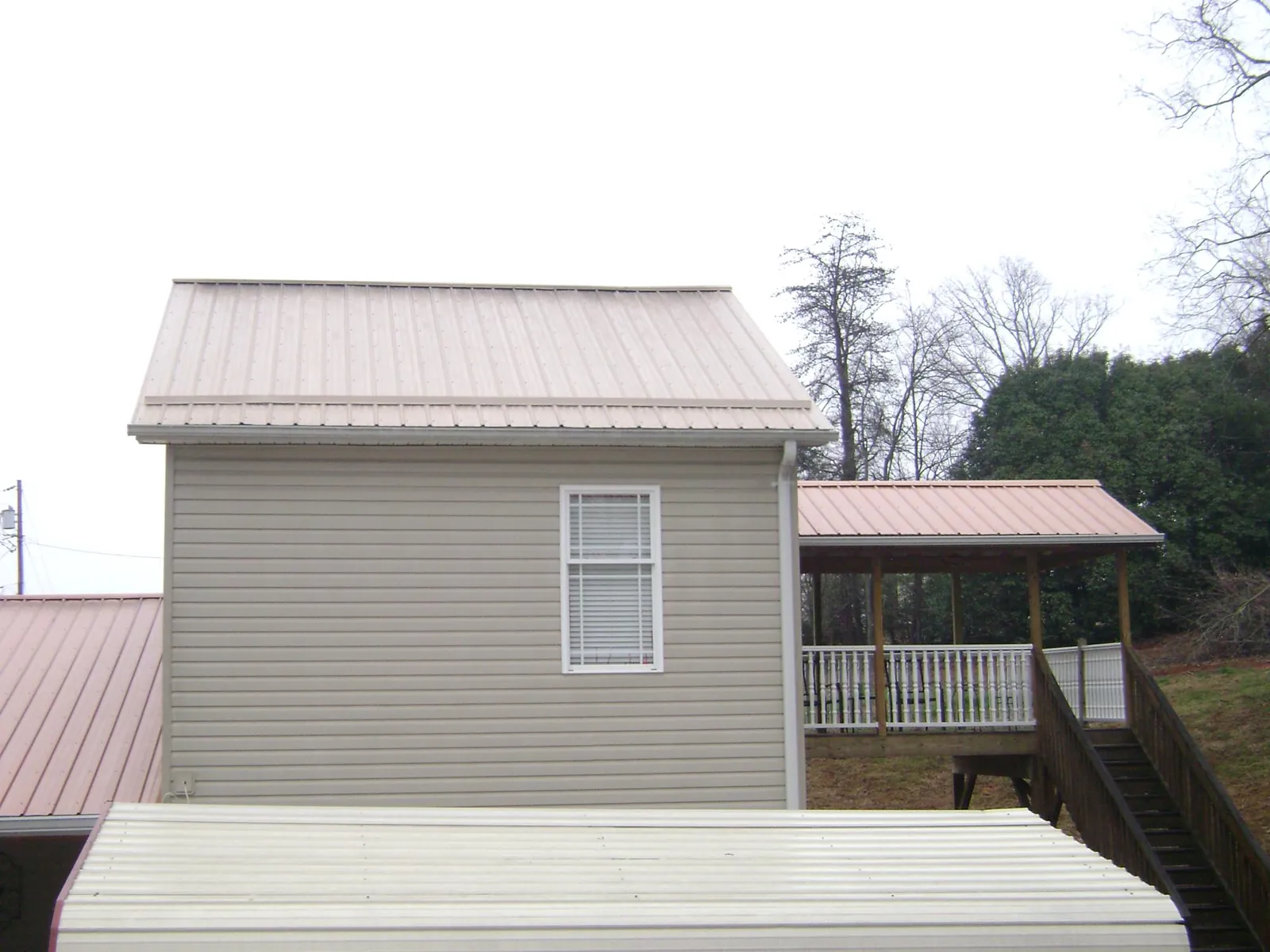 Tan metal roofs on a two story addition and attached porch, from a Roof Replacement job in Ravenswood