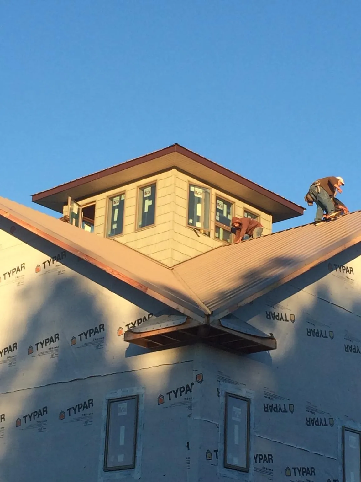 Roofers working around a rooftop cupola on a new metal roof at sunset — Roof Waterproofing in Ravenswood by Roofing Brothers